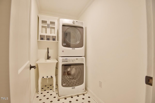 clothes washing area with stacked washer / dryer, laundry area, crown molding, and baseboards