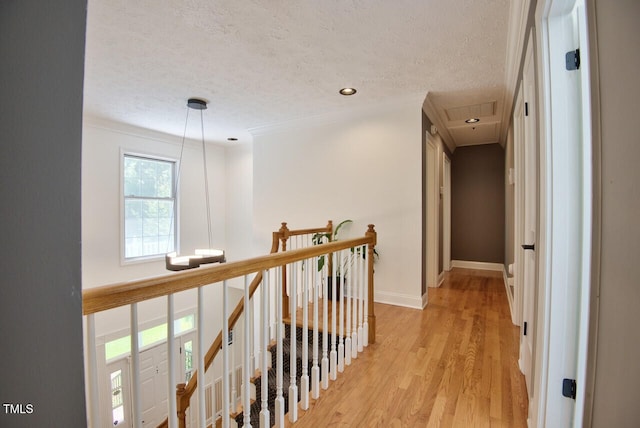 corridor featuring baseboards, light wood-style flooring, a textured ceiling, an upstairs landing, and recessed lighting