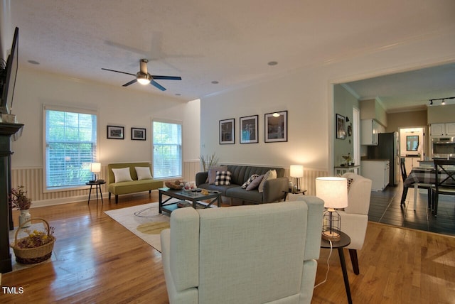 living area featuring ornamental molding, a ceiling fan, and wood finished floors