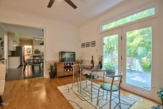 dining space with crown molding, a ceiling fan, wood finished floors, and visible vents