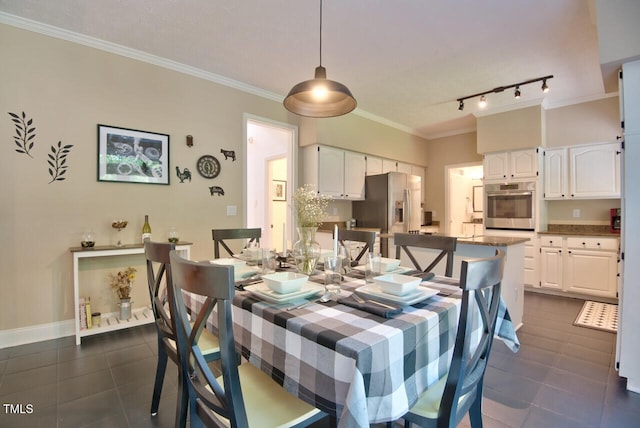 dining area with crown molding, dark tile patterned floors, and track lighting