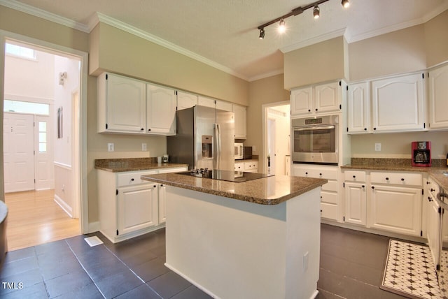 kitchen with ornamental molding, a center island, dark tile patterned floors, white cabinetry, and appliances with stainless steel finishes