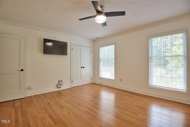 unfurnished bedroom featuring crown molding, light wood-style flooring, a textured ceiling, and baseboards