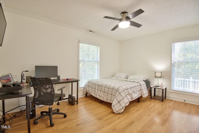 bedroom with baseboards, visible vents, ornamental molding, and light wood-style flooring