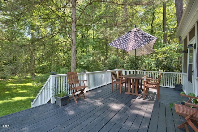 wooden terrace with a view of trees and outdoor dining space