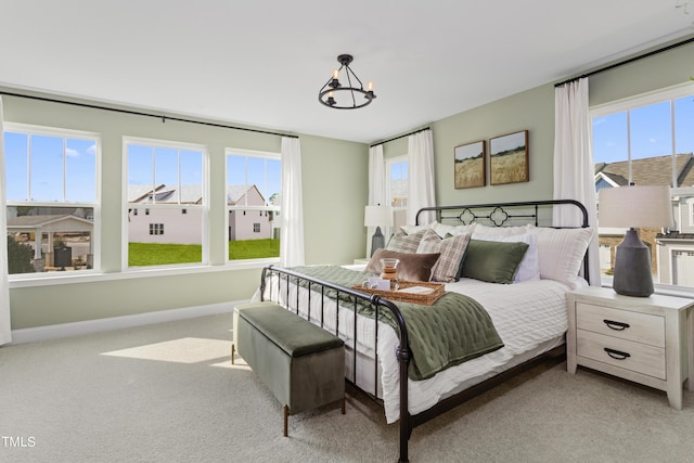 carpeted bedroom featuring a chandelier and multiple windows