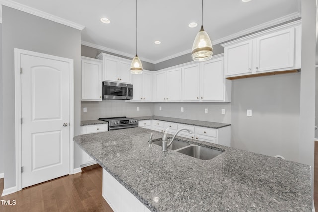 kitchen featuring pendant lighting, dark stone counters, white cabinets, sink, and appliances with stainless steel finishes