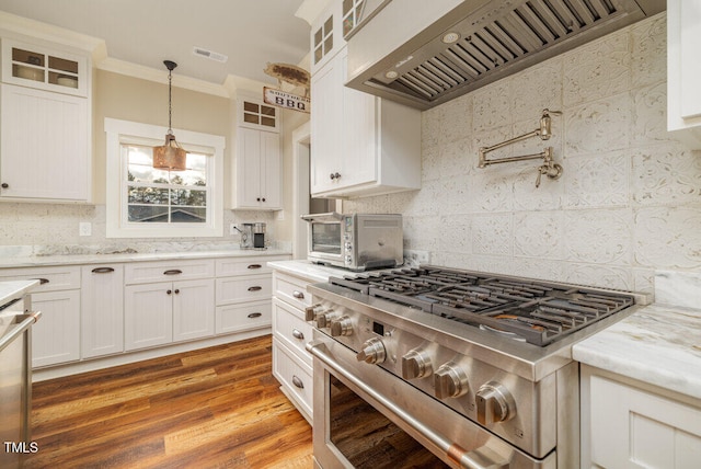 kitchen with white cabinetry, stainless steel appliances, hardwood / wood-style flooring, custom exhaust hood, and ornamental molding