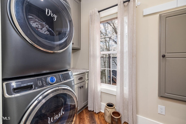 clothes washing area with dark hardwood / wood-style flooring, cabinets, and stacked washer / drying machine