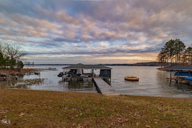 view of dock with a water view and a lawn