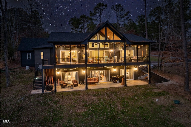 back house at night featuring a patio and a deck