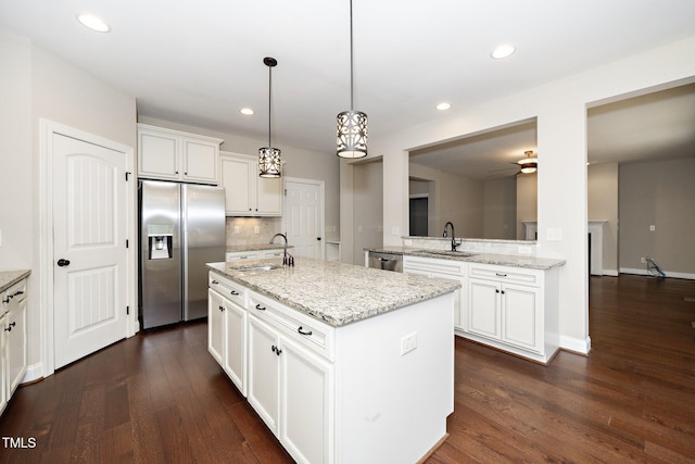 kitchen featuring appliances with stainless steel finishes, an island with sink, a sink, and white cabinetry