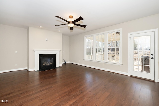 unfurnished living room with ceiling fan, dark wood-type flooring, a fireplace with flush hearth, and baseboards