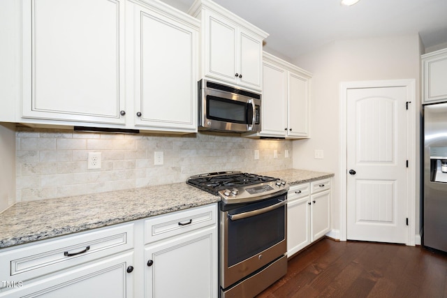 kitchen featuring dark wood-style floors, appliances with stainless steel finishes, white cabinets, and light stone counters