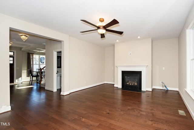 unfurnished living room with visible vents, baseboards, a ceiling fan, a fireplace with flush hearth, and dark wood-type flooring