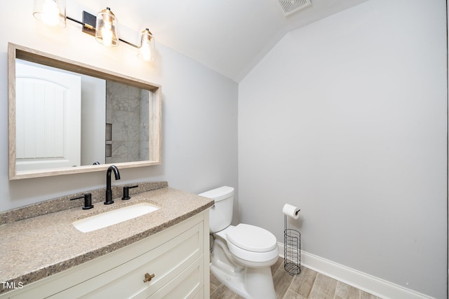 bathroom with visible vents, lofted ceiling, toilet, wood finished floors, and vanity