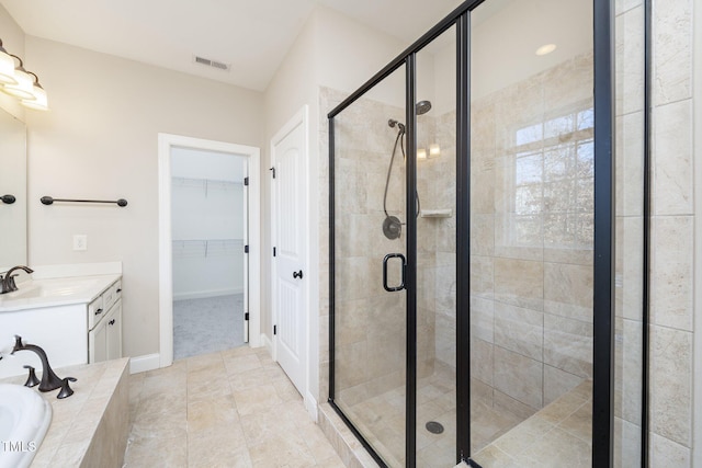 bathroom with a stall shower, visible vents, a walk in closet, vanity, and a bath