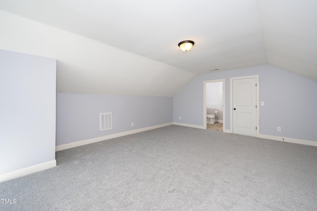 additional living space featuring carpet flooring, visible vents, vaulted ceiling, and baseboards