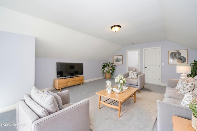 carpeted living area with lofted ceiling and baseboards