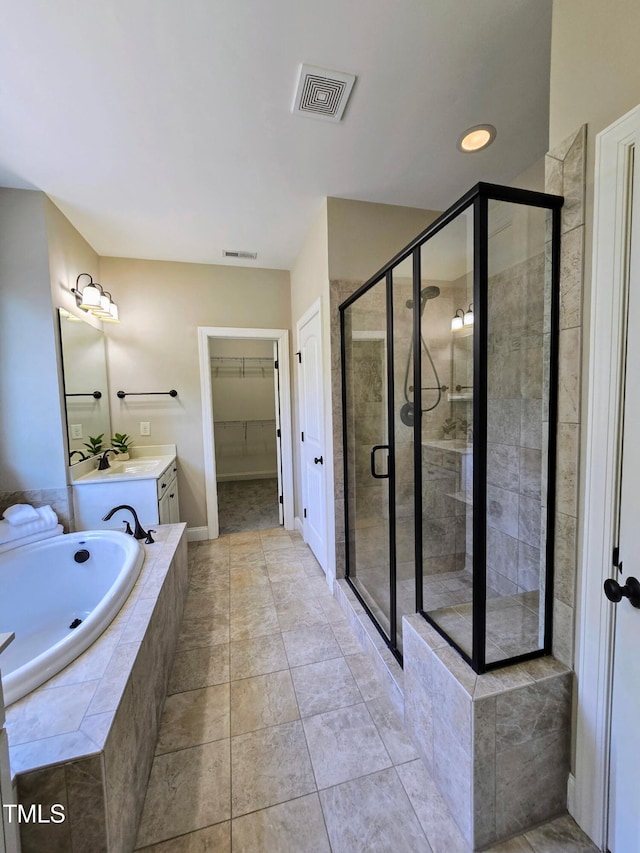 bathroom with visible vents, a garden tub, vanity, a spacious closet, and a stall shower