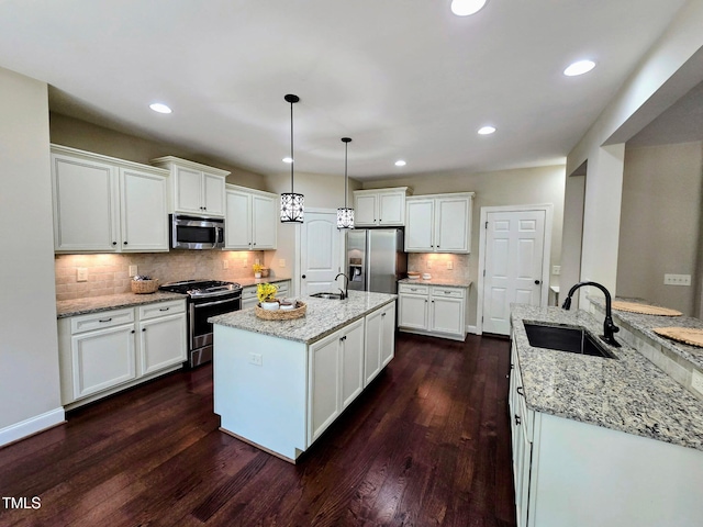 kitchen featuring a sink, appliances with stainless steel finishes, dark wood-style flooring, and an island with sink