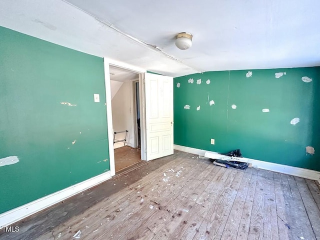 unfurnished room with hardwood / wood-style floors and vaulted ceiling