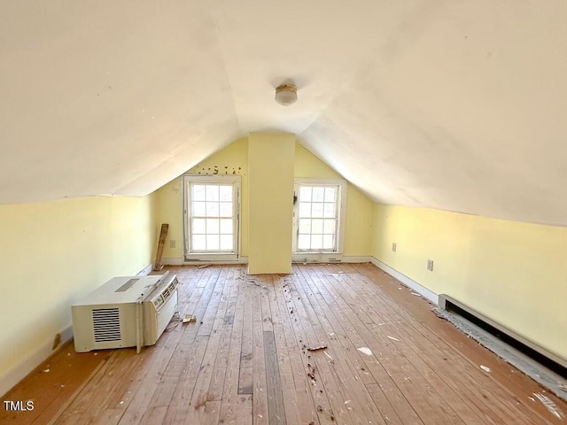 bonus room featuring vaulted ceiling, light hardwood / wood-style flooring, and a baseboard heating unit