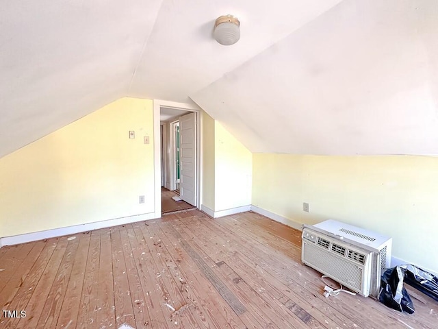 additional living space featuring light hardwood / wood-style floors, lofted ceiling, and a wall unit AC