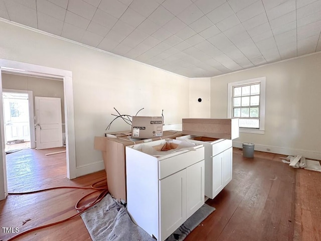 kitchen with white cabinetry, ornamental molding, and hardwood / wood-style flooring