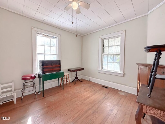 sitting room featuring ceiling fan, light hardwood / wood-style floors, crown molding, and a wealth of natural light