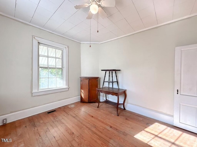 empty room with light wood-type flooring, ceiling fan, and ornamental molding