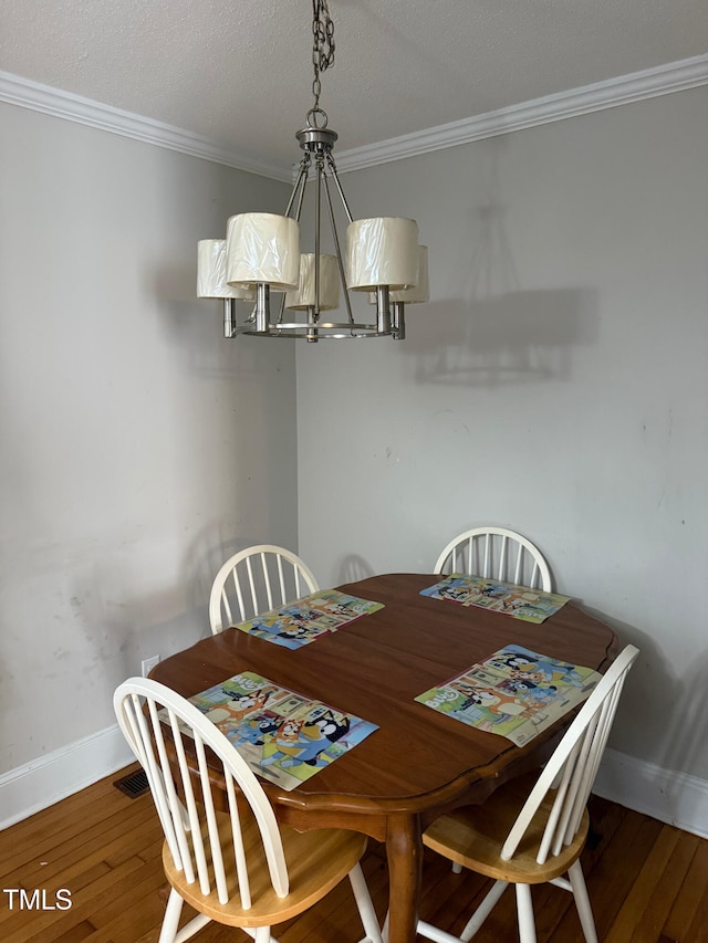 dining area featuring dark hardwood / wood-style flooring, a notable chandelier, ornamental molding, and a textured ceiling