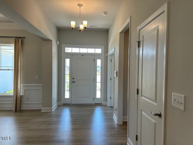 entrance foyer with dark hardwood / wood-style floors and a notable chandelier