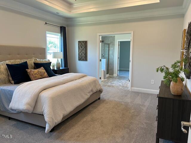 bedroom featuring carpet flooring, a raised ceiling, ensuite bath, and crown molding