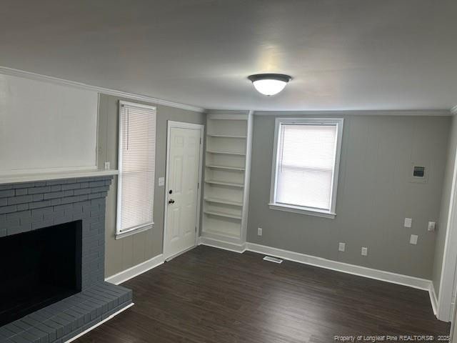 1016 E 8th St, Lumberton, NC 28358 - unfurnished living room with crown molding, dark hardwood / wood-style floors, and a brick fireplace
