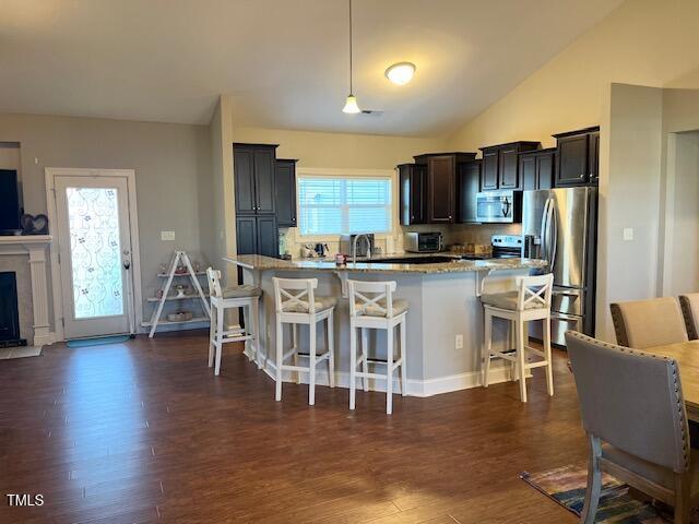 kitchen with a center island, hanging light fixtures, dark hardwood / wood-style floors, a kitchen bar, and stainless steel appliances