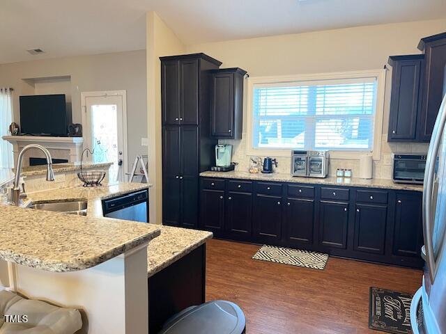 kitchen featuring sink, stainless steel appliances, a kitchen breakfast bar, dark hardwood / wood-style floors, and a center island with sink