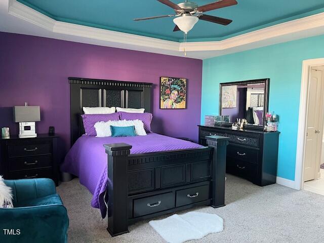 carpeted bedroom with a tray ceiling and ceiling fan