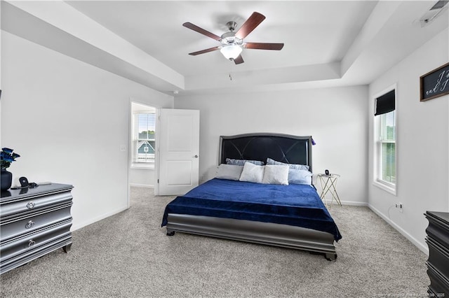 carpeted bedroom featuring a raised ceiling and ceiling fan