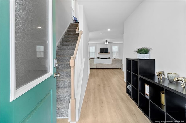 foyer entrance with stairs, a ceiling fan, and wood finished floors