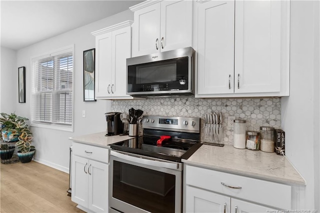 kitchen featuring light wood finished floors, decorative backsplash, light stone countertops, stainless steel appliances, and white cabinetry