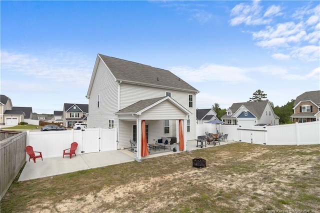 back of property with a fire pit, a patio, a fenced backyard, a residential view, and a gate