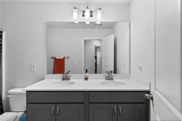 full bath with double vanity, visible vents, toilet, and a sink