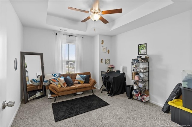 living room with a tray ceiling, carpet flooring, and baseboards