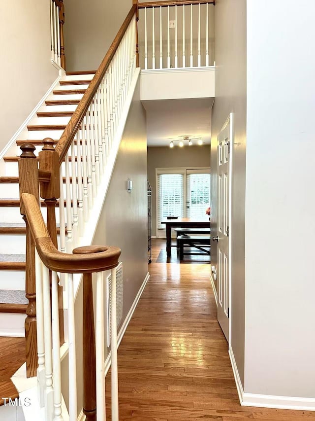 hallway with hardwood / wood-style floors and a high ceiling