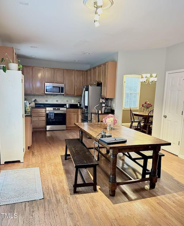 kitchen featuring stainless steel appliances, a chandelier, light hardwood / wood-style floors, and decorative backsplash