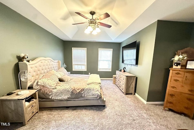 carpeted bedroom with a raised ceiling and ceiling fan