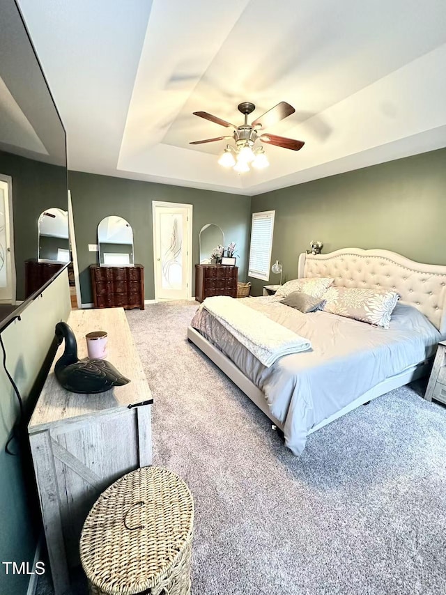 carpeted bedroom with ceiling fan and a raised ceiling