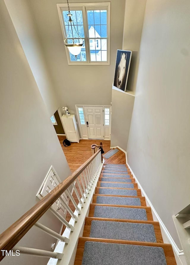 staircase featuring hardwood / wood-style flooring and a high ceiling