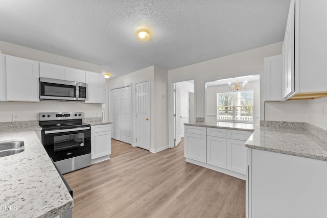 kitchen featuring stainless steel appliances, a textured ceiling, light wood-type flooring, white cabinetry, and a sink